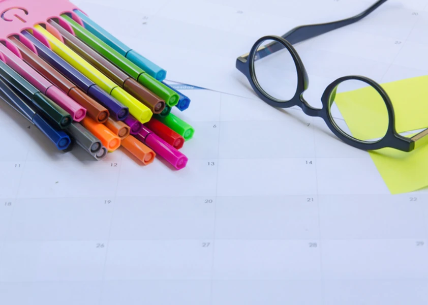 Lunettes et crayons de couleur sur un calendrier