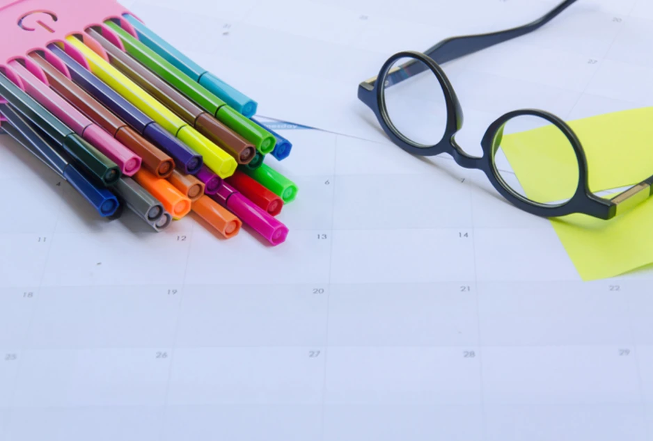 Lunettes et crayons de couleur sur un calendrier